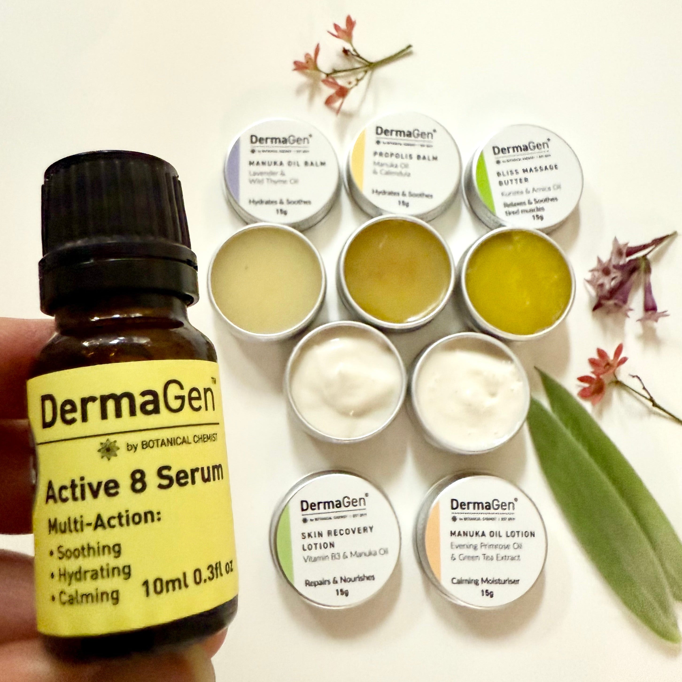 Hand holding a bottle of DermaGen Active 8 Serum with various skincare products on a white background